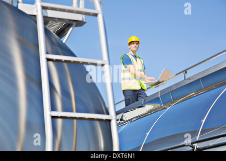 Worker using laptop on platform above stainless steel milk tanker Stock Photo