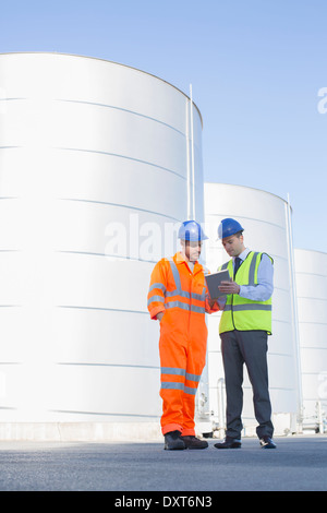 Businessman and worker using digital tablet next to silage storage towers Stock Photo