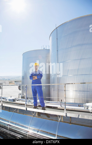 Worker with arms crossed on platform above stainless steel milk tanker Stock Photo