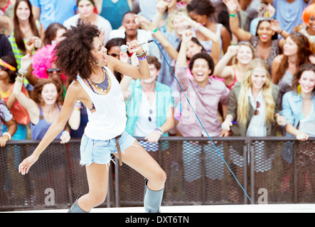 Fans cheering for performer singing on stage at music festival Stock Photo