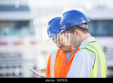 Workers using digital tablet near trucks Stock Photo