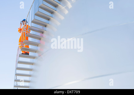 Worker using walkie-talkie on stairs along silage storage tower Stock Photo
