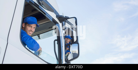 Portrait of smiling truck driver leaning out window Stock Photo