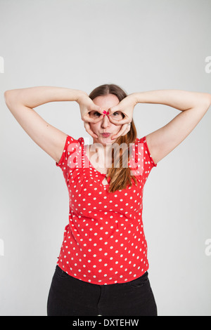 Studio portrait of attractive woman with pursed lips looking through finger goggles Stock Photo