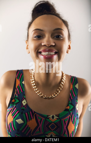 Close up portrait of pretty young woman making a funny face. Female model against grey background Stock Photo