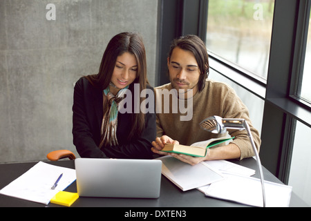 Young man and woman with laptop and book preparing for exams. university students working hard for final exams in library. Stock Photo