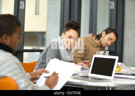 Cheerful young woman looking at camera while studying. university students studying with books and laptop in library. Stock Photo
