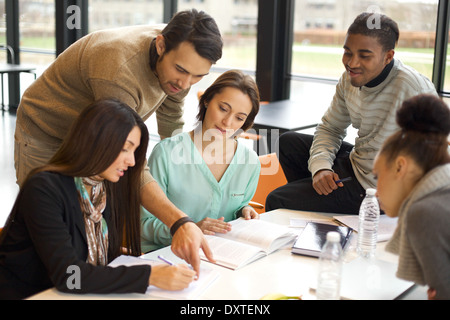 Multiethnic group of young students doing their studies together at a table. Mixed race people in cooperation. Stock Photo