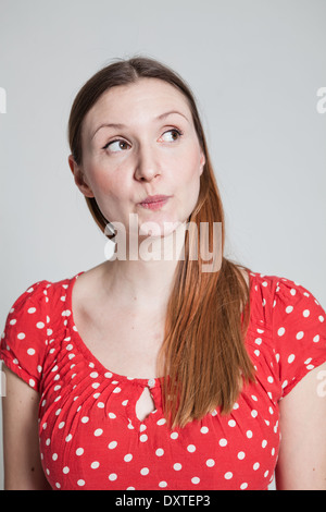 Studio portrait of thoughtful looking attractive woman with pursed lips looking to side Stock Photo