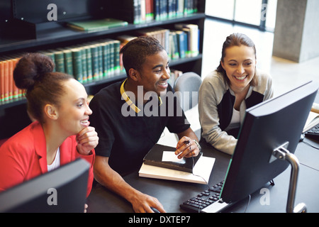 Diverse group of students using computer for finding information for their academic project. Happy young people sitting at table Stock Photo