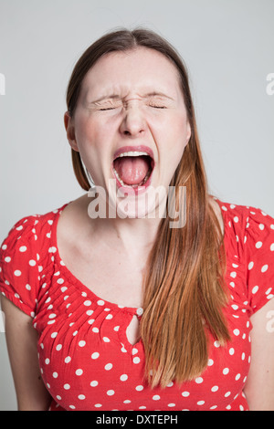 Studio portrait of stressed attractive woman shouting with eyes closed Stock Photo