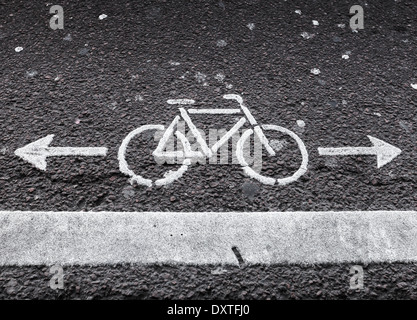 Bicycle lane. White road marking with arrows on dark asphalt Stock Photo