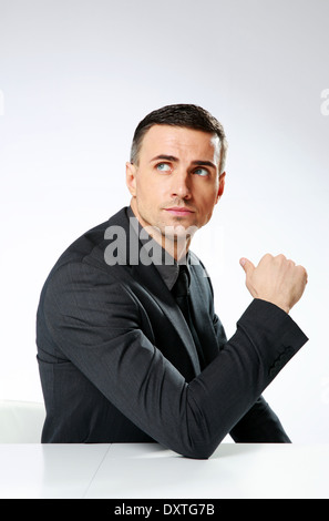 Thoughtful businessman sitting at the table and looking away isolated on a white background Stock Photo