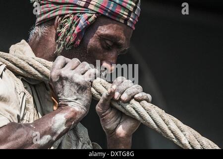 A worker is dragging a heavy pull rope in a shipbreaking yard in Chittagong. Once the beach at the shipwrecking places in Chittagong, Bangladesh were white and clean. Today Chittagong is partially soaked with oil and toxic mud. Chittagong is one of the wor Stock Photo