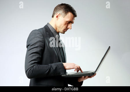 Confident businessman using laptop on gray background Stock Photo