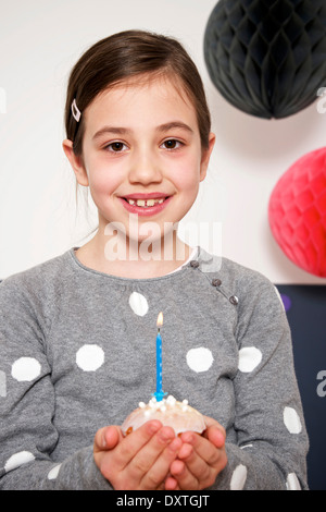 Girl on birthday party holding cupcake with burning candle, Munich, Bavaria, Germany Stock Photo