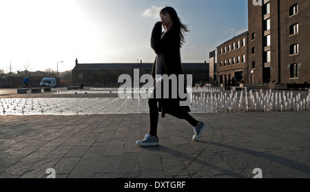 Young Asian woman walking past fountain at UAL University of the Arts CSM Central St Martins,  Kings Cross London N1  KATHY DEWITT Stock Photo