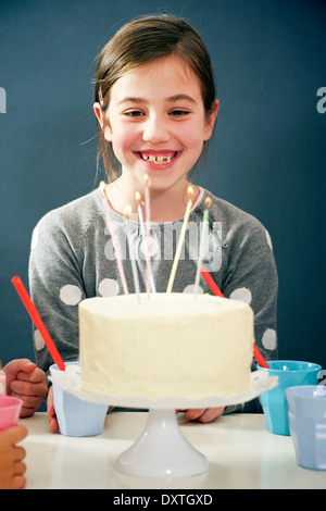 Girl on birthday party looking at candles on cake, Munich, Bavaria, Germany Stock Photo