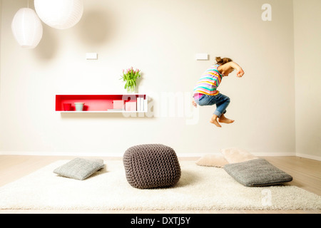 Girl jumping across cushions, having fun, Munich, Bavaria, Germany Stock Photo