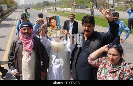 Pakistan, Islamabad. 31st Mar, 2014. Supporters of former Pakistani military ruler Pervez Musharraf flash victory signs as they hold a picture of Musharraf outside a special court hearing treason case against him in Islamabad on March 31, 2014. A Special Court in Pakistan charged Musharraf with high treason -- a crime that carries the death penalty or life imprisonment. Credit:  PACIFIC PRESS/Alamy Live News Stock Photo