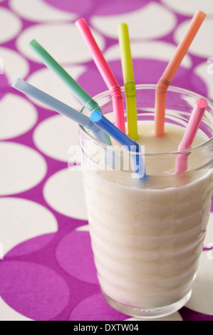 Glass of milk with colored straws Stock Photo