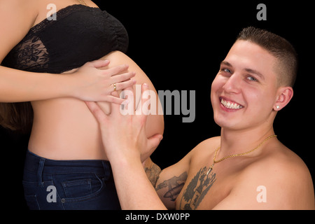 Smiling father holding his wife's pregnant belly in his hands Stock Photo
