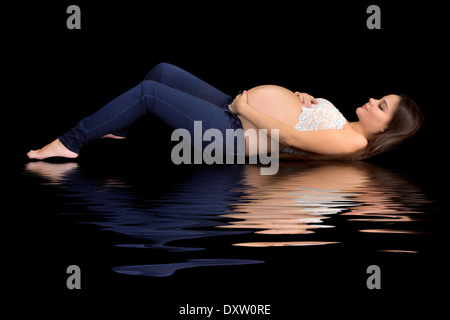 Attractive young pregnant woman reflected on a black background Stock Photo