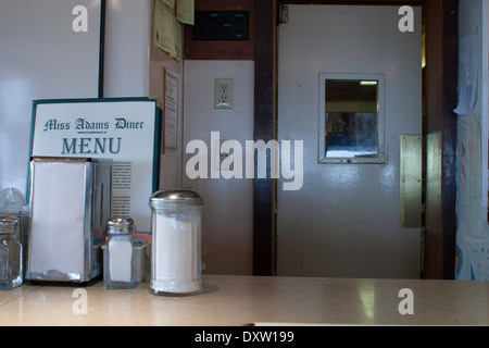 Diner menu sits on the counter in a small town diner. Door to kitchen is in rear. Stock Photo