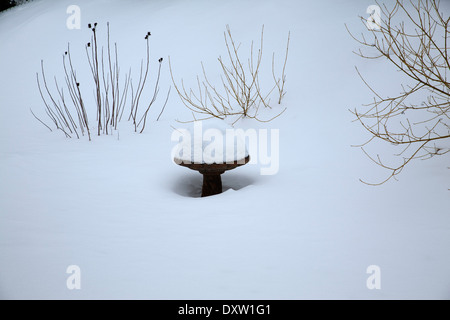 Deep snow piles on top of birdbath in a New England back yard. Stock Photo