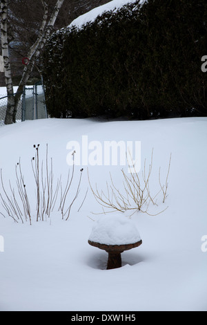 Deep snow piles on top of birdbath in a New England back yard. Stock Photo