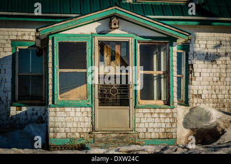 Snow drifts around the front entrance of a deteriorated and abandoned old house. Stock Photo