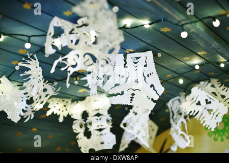 Paper snowflakes hanging on a ceiling with twinkly lights. Stock Photo