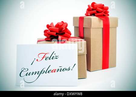 some gifts and the text feliz cumpleanos, happy birthday written in spanish in a signboard Stock Photo