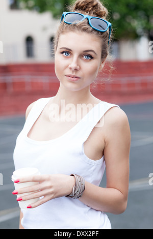 beautiful young girl in white t-shirt holds white to-go cup at basketball court Stock Photo