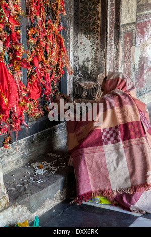 India, Dehradun. A visitor ties bits of red cloth to the window latticework as a symbol of prayers offered at a Sikh Temple. Stock Photo