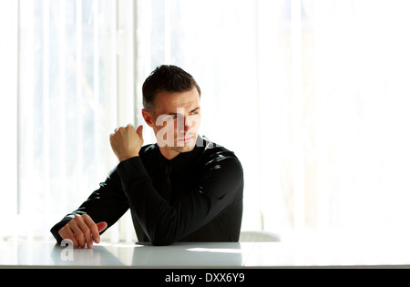 Thoughtful businessman sitting at the table and looking away Stock Photo