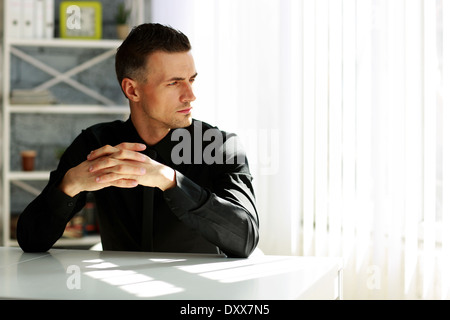 Pensive businessman sitting at the table in office Stock Photo