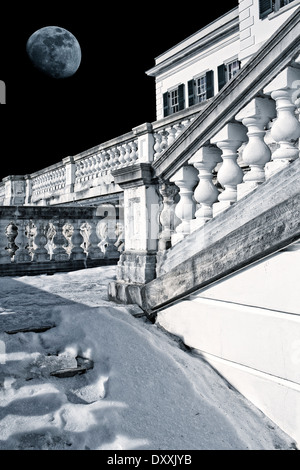 Snow covered stair case leading up to a gilded age mansion under a full moon. Stock Photo