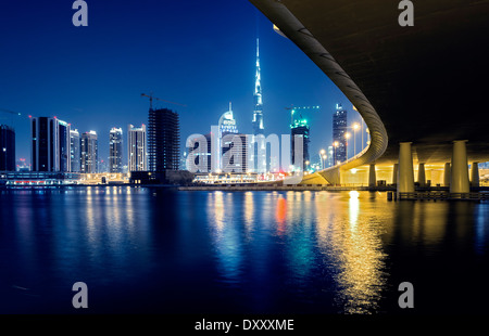 Night view of skyline of new Business Bay District towards Burj Khalifa tower from The Creek river in Dubai United Arab Emirates Stock Photo
