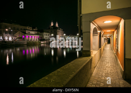 River Limmat in Zurich at Night looking across river to buildings on other side and down a covered walkway Stock Photo