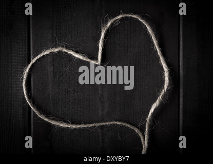 Closeup of hemp twine or string in shape of a heart on dark wood Stock Photo