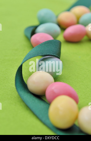 small colorful eggs with ribbon on green background Stock Photo