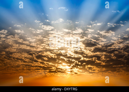 Dramatic Sunbeam through cloud blue and orange twilight sky background Stock Photo