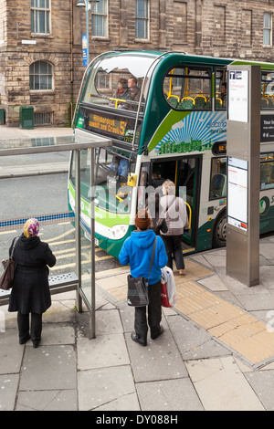 UK Public transport. People standing at a bus stop while getting on a bus in Sheffield city centre, South Yorkshire, England, UK Stock Photo