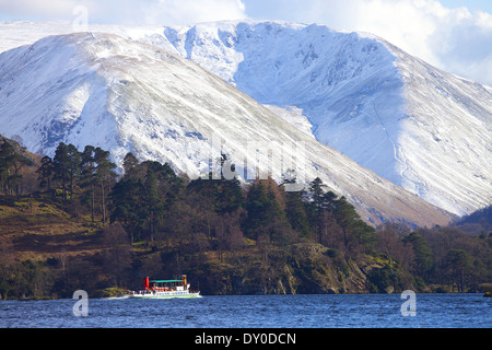 Tourists taking a trip on a steamer (boat) a lake, with Snow covered hills in the background. Ullswater, Lake District, Cumbria. Stock Photo