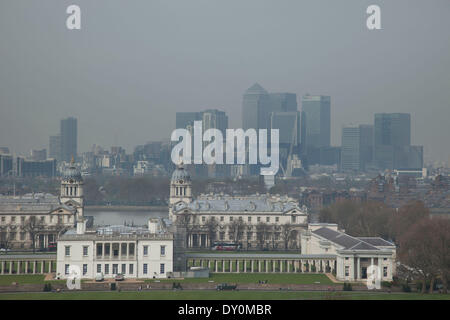 London, UK. 2nd April 2014. Industrial pollution from Europe and dust from the Sahara region creates a layer of smog over the City of London. Barely visible through the polluted air, the buildings seem to disappear into the poor air quality. View from Greenwich Park towards the skyline at Canary Wharf financial district across Greenwich Maritime Museum. Credit:  Michael Kemp/Alamy Live News Stock Photo