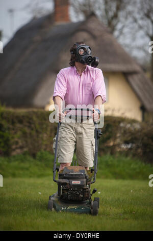 Arkesden, Essex . Man mowing the lawn wearing a gas mask as a precaution  against Saharan  Dust pollution Stock Photo