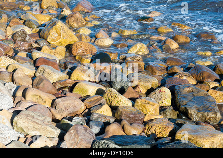 Waves Trickle Over Rocks Bathing in Sunshine on the North East Coast near Beadnell Northumberland England United Kingdom UK Stock Photo