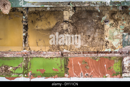 An old interior wall with fittings removed revealing layers of paint and plaster. Stock Photo