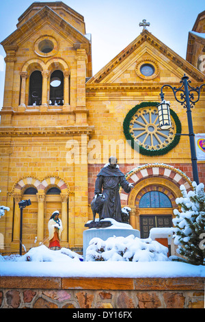 Bronze statue of St. Francis of Assisi with wolf and St. Kateri, in snowy winter scene stands in front of the Cathedral Basilica Stock Photo